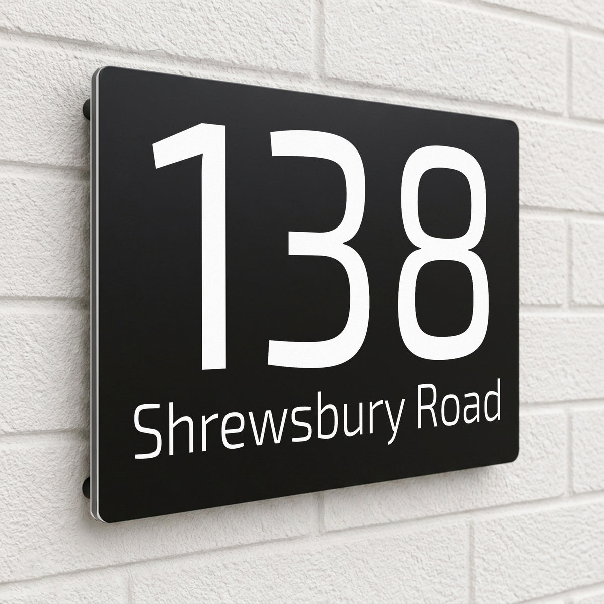 Black composite house sign personalised with '138 Shrewsbury Road' in a rounded sans-serif font