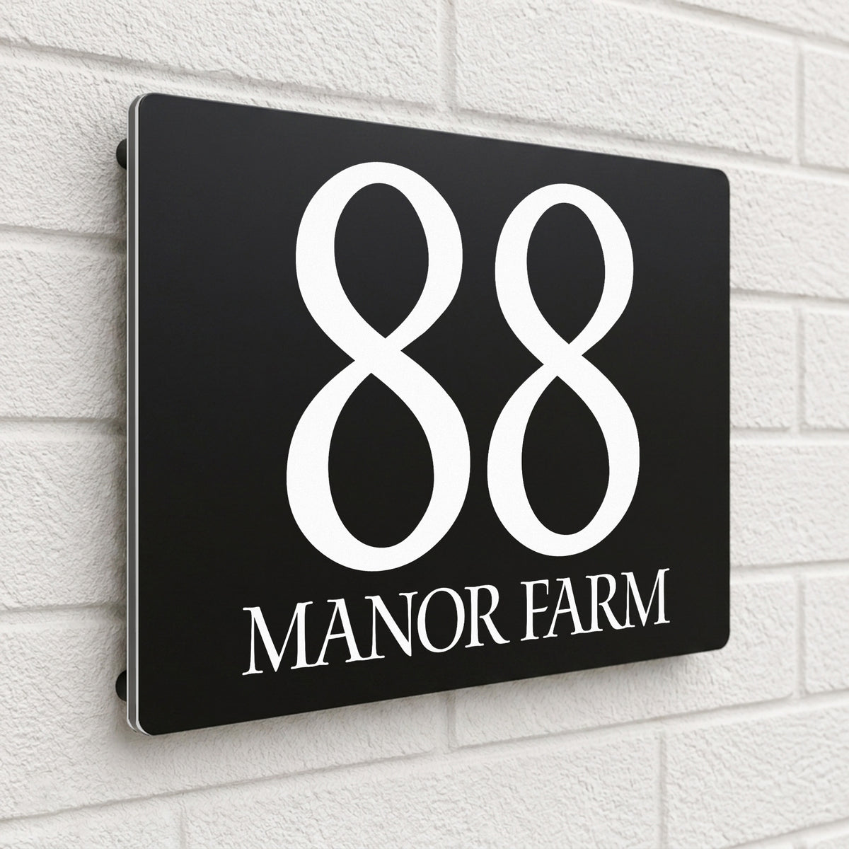 Black composite house sign personalised with '88 Manor Farm' in an elegant serif typeface