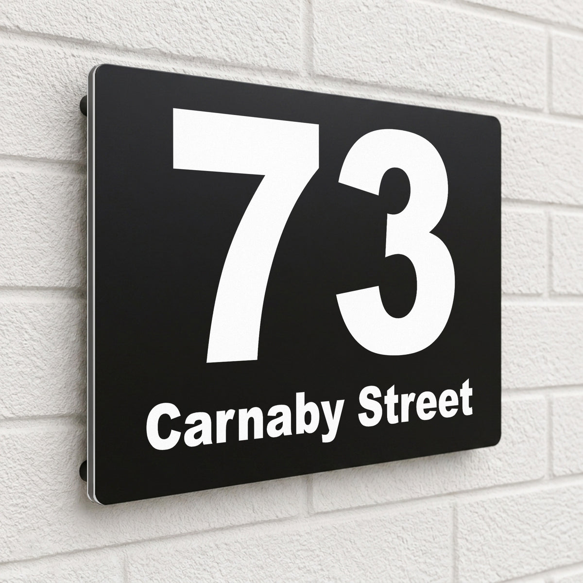 Black composite house sign personalised with '73 Carnaby Street' in a heavy modern font