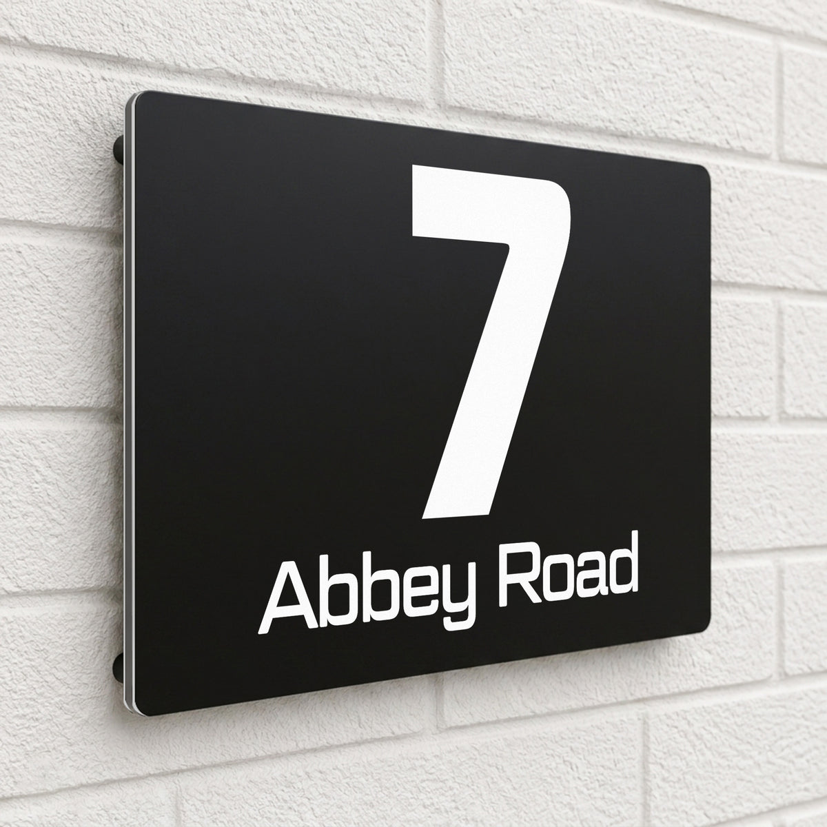 Black composite house sign personalised with '7 Abbey Road' in a bold sans-serif font