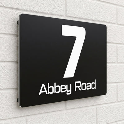 Black composite house sign personalised with '7 Abbey Road' in a bold sans-serif font