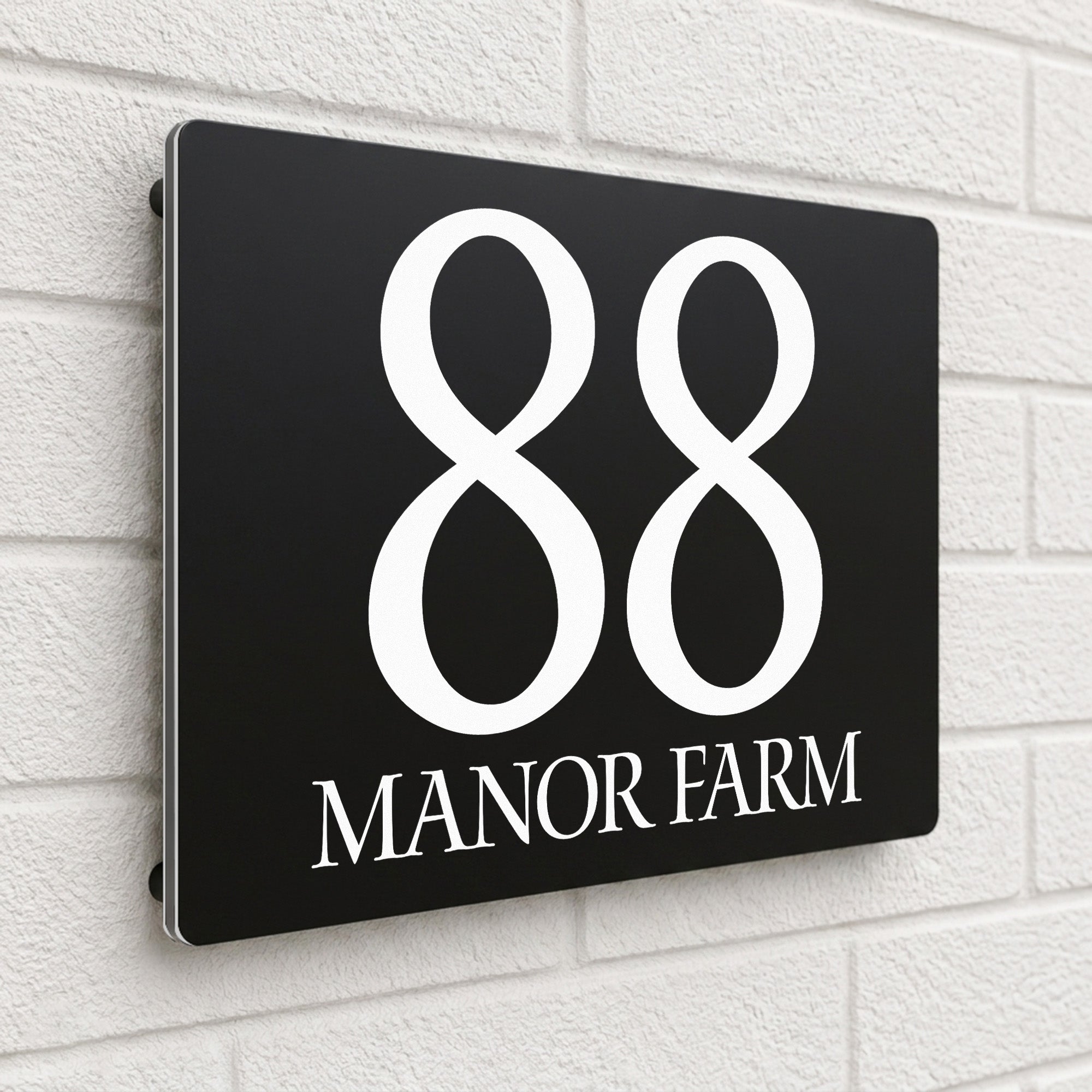 Black composite house sign personalised with '88 Manor Farm' in an elegant serif typeface