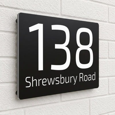 Black composite house sign personalised with '138 Shrewsbury Road' in a rounded sans-serif font